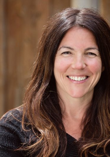 Happy smiling woman with long brown hair sitting outside