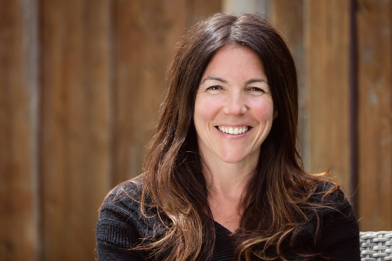 Happy smiling woman with long brown hair sitting outside